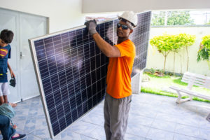 Funcionário da SolarON chagando com as placas fotovoltaicas na OSDM